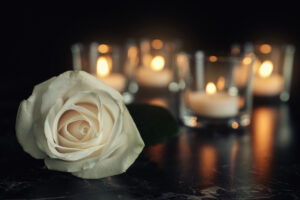  A white rose with four lit candles in the backgrounds.