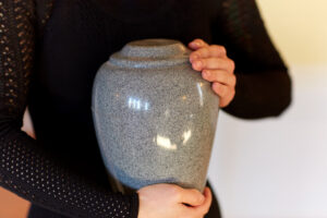 a person wearing black holding an urn.