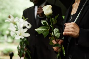 people at a funeral holding white flowers and an umbrella at a funeral.